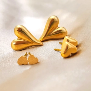 Vue macro de boucles d'oreilles cœur en or poli et mat sur fond de soie douce