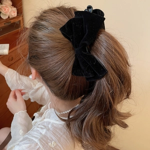 Close-up of a large black velvet bow hair clip worn on a low ponytail hair style