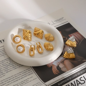 Flat lay of retro gold stainless steel earrings with pearls on aesthetic background