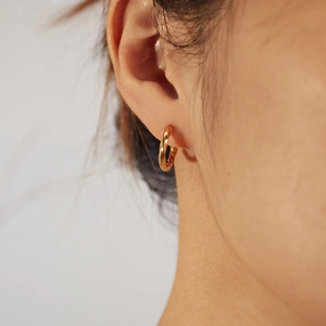 Close-up of golden Mobius twist hoop earring worn on model for actual size reference