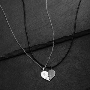 Detail of interlocking heart pendants with engraved hand-holding pattern for couples