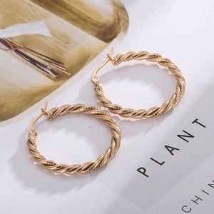 Close-up of golden twisted rope hoop earrings with textured finish and secure latch back