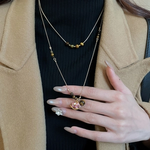 Gros plan sur un collier double rang doré en œil de tigre avec pendentif cheval rose