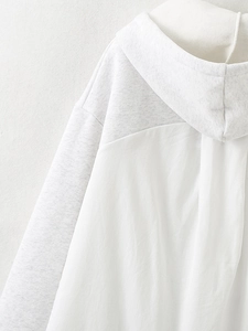 Detailed close-up of light gray and white patchwork stitching on a casual hooded sweatshirt