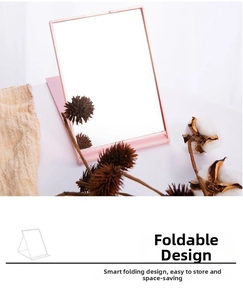 Close-up of pink foldable makeup mirror showing its adjustable stand and slim profile