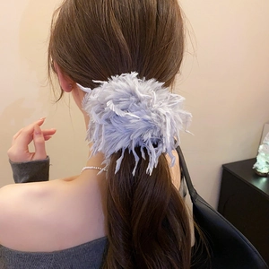 Détail du chouchou en plumes bleu clair porté sur une coiffure en queue de cheval