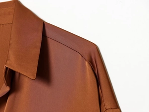 Detail of square neckline and shoulder seams on brown satin long sleeve blouse
