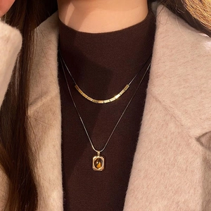 Detail of 18k gold plated double-layered necklace set with oval tiger eye stone pendant