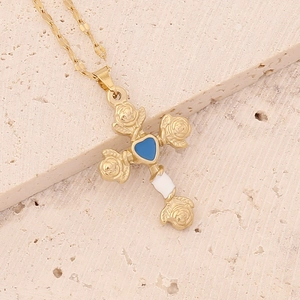Gold cross necklace with rose relief and blue heart pendant on a stone background