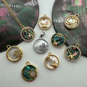 Macro detail of 18K gold shell pendants with snowflake and rabbit charms for DIY jewelry