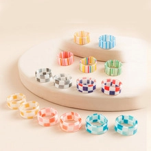 Close-up of sixteen colorful acrylic resin rings with checkered and striped patterns