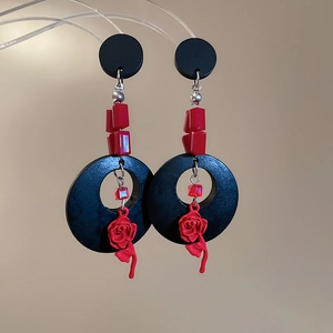 Vue détaillée de longues boucles d'oreilles avec roses rouges et perles noires géométriques