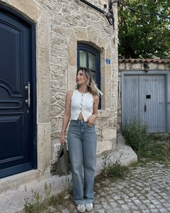 Photo en extérieur d'un gilet en maille blanc avec un jean bleu clair et un cabas vert