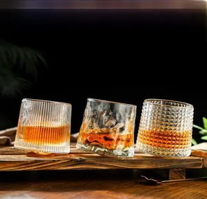 Close-up of three textured rotating whiskey glasses on a dark wood tray with amber liquid