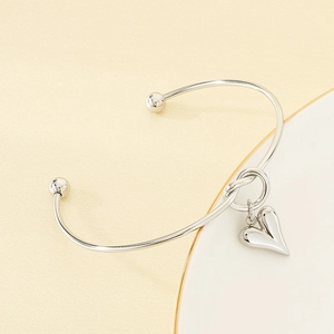 Detail view of silver heart pendant bracelet with polished metallic finish and ball ends