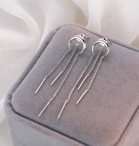 Dettaglio macro di orecchini a mezzaluna d'argento con tre delicate nappe a catena lunga