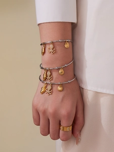 Detail of silver bangles with gold ocean charms and rhinestone octopus pendant on model