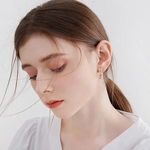 Close-up of elegant C-shaped earrings with pearls and crystals on a female model