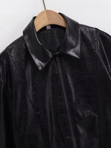 Detail shot of black faux leather jacket featuring a lapel collar and silver metal zipper
