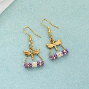 Detail of vintage gold dragonfly earrings with purple and white beaded accents