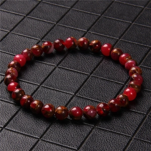 Close-up of natural red agate stone beads with distinctive texture on a crystal bracelet