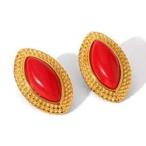 Detailed macro shot of vintage gold earrings with large oval red stones on white background