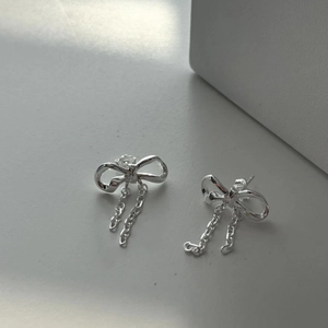 Detail view of 925 silver bow stud earrings with delicate hanging tassel chains