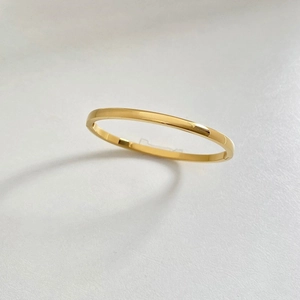 Detailed close-up of a polished gold stainless steel bracelet with floral engraving