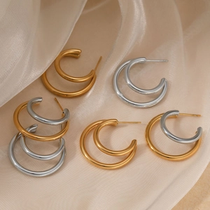 Polished C-shape double hoop earrings in gold and silver finish on beige silk