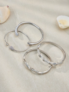 Détails de quatre bracelets argentés avec zircons sertis et textures organiques élégantes