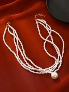 Detail of multi-layer white pearl necklace with large pendant on red silk background