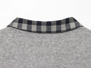 Detailed close-up of grey knit fabric with contrast plaid pattern collar stitching