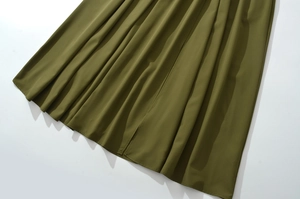 Detailansicht des olivgrünen Kleidsaums mit glattem Stoff und elegantem Seitenschlitz