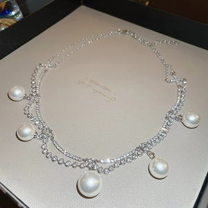 Detail shot of a double-layered pearl necklace with crystal accents on a neutral base