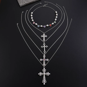 Detail of five-piece silver cross necklaces with colorful gemstones and pearls on stone