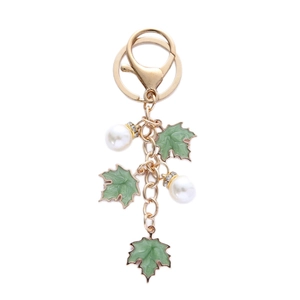 Elegant gold keychain featuring green maple leaf pendants and white pearls on white background