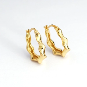 Elegant gold twisted hoop earrings with a textured wavy design in polished metal finish
