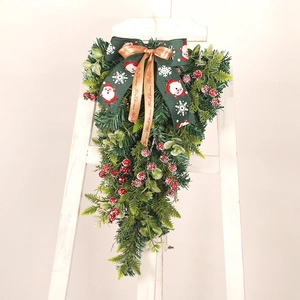 Christmas teardrop swag with green pine, red berries and festive Santa Claus bow