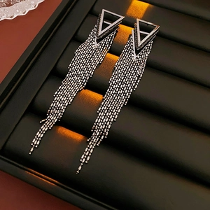 Detail of silver triangle earrings with black pavé stones and long hanging chain fringes