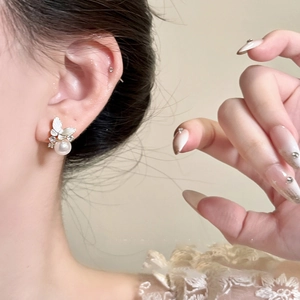 Detailed close-up of a silver butterfly earring with shimmering pearls and zircon stones