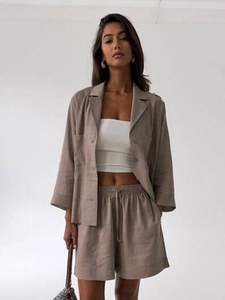 Detail of high-waisted drawstring shorts and lightweight linen blend shirt in taupe