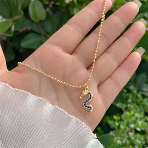 Close-up of golden dragon pendant featuring dark blue zircon inlay and fine bead chain