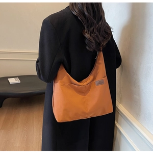 Large orange tote bag in water-resistant fabric worn over a black winter coat