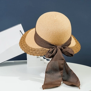Detail of wide brim straw hat with wavy edges and brown chiffon bow ribbon decor