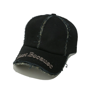 Detailed macro view of distressed edges and 'Just Because' embroidery on black cotton cap
