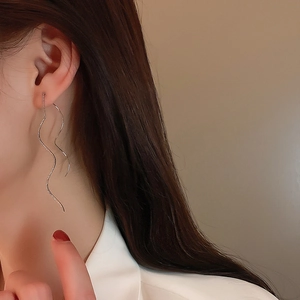 Detail shot of elegant silver wavy tassel earring showing a graceful draping effect