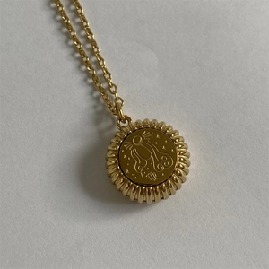 Macro shot of gold zodiac pendant with ribbed edges and abstract engraved symbol