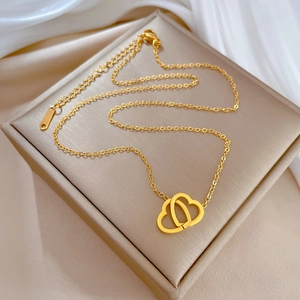Detail of a golden double heart pendant necklace displayed on a beige jewelry box