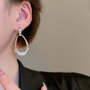 Close-up of a silver teardrop earring with pavé rhinestones on a female model