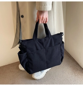 Detail of black corduroy tote bag showing multiple pockets and vertical ribbed texture